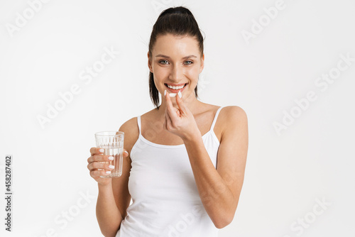 European woman wearing underwear smiling while taking vitamins