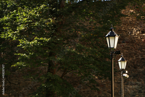 Fototapeta Naklejka Na Ścianę i Meble -  Old lantern on a background of blue sky and green trees.