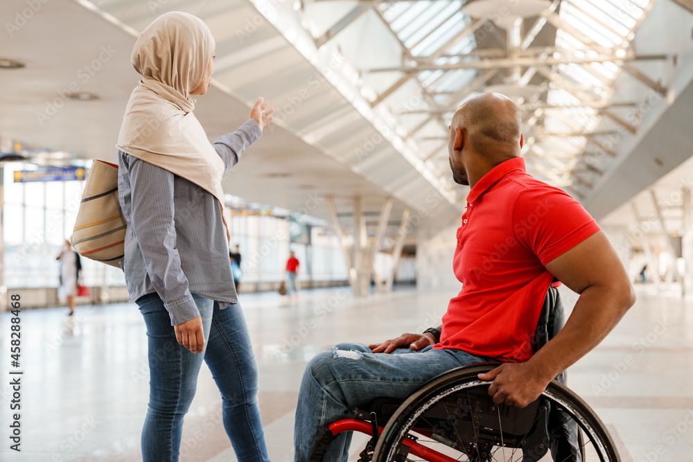 Obraz premium Muslim woman and disabled man gesturing while talking to each other