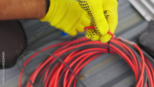 Electrician technician worker with wire stripper plier prepares the electric cable in electrical system. Electrician installing wires. A professional electrician removes electrical insulation