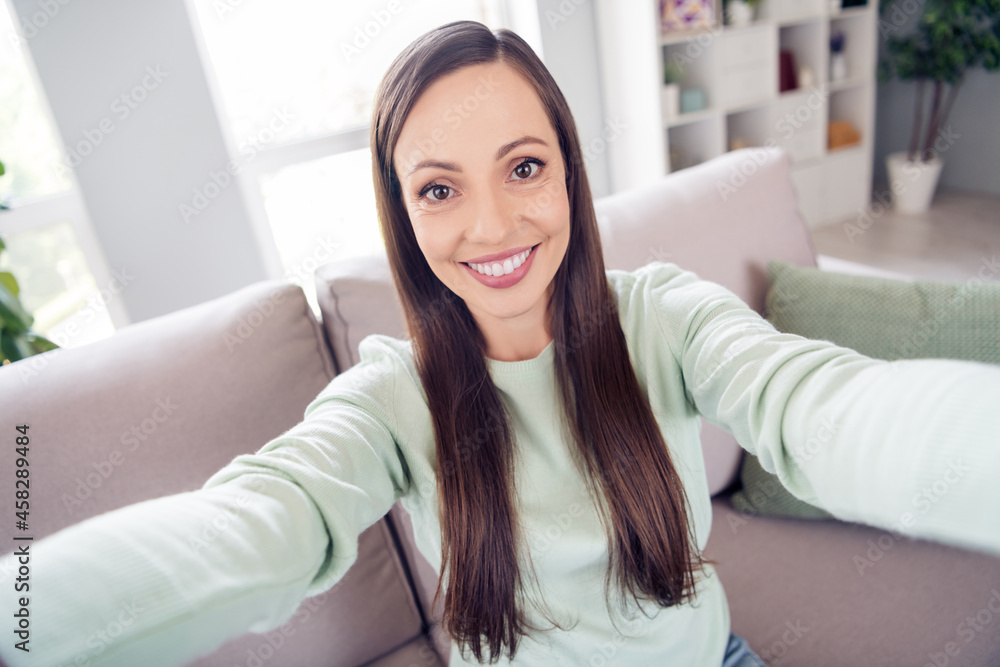 Photo of pretty shiny mature lady wear teal pullover smiling sitting couch recording video indoors house room Photo of pretty shiny mature lady wear teal pullover smiling sitting couch recording video indoors house room