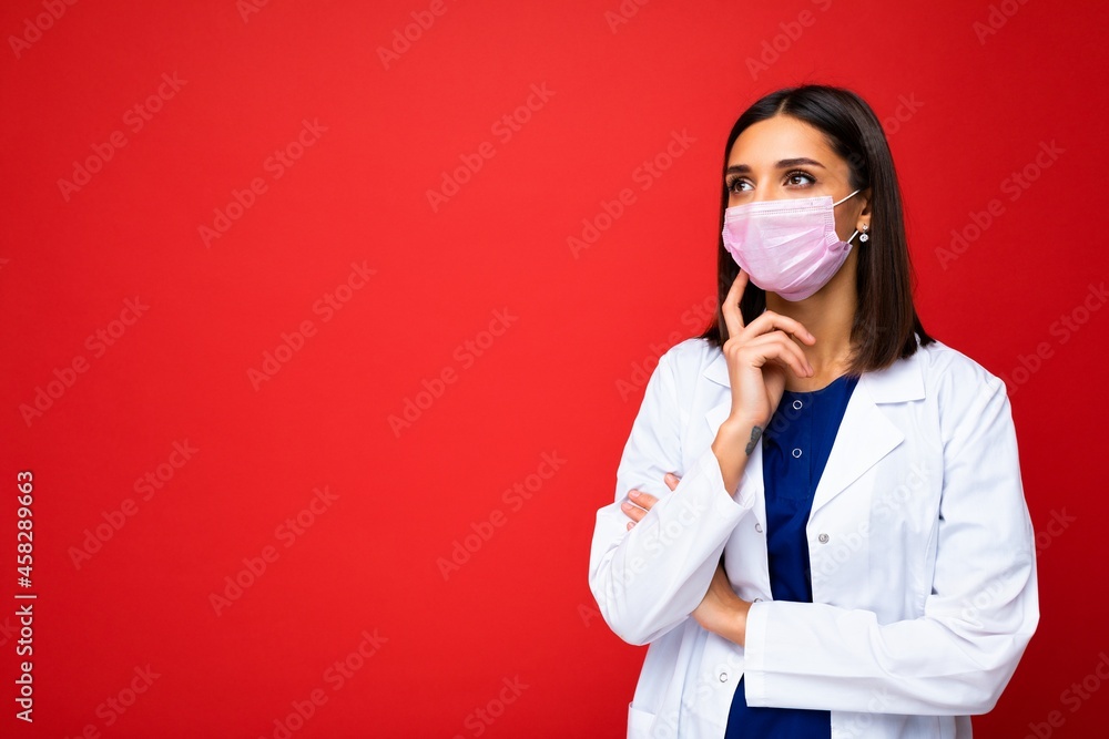 Young woman wearing an anti virus protection mask to prevent others from corona COVID-19 and SARS cov 2 infection isolated over red background Young woman wearing an anti virus protection mask to prevent others from corona COVID-19 and SARS cov 2 infection isolated over red background