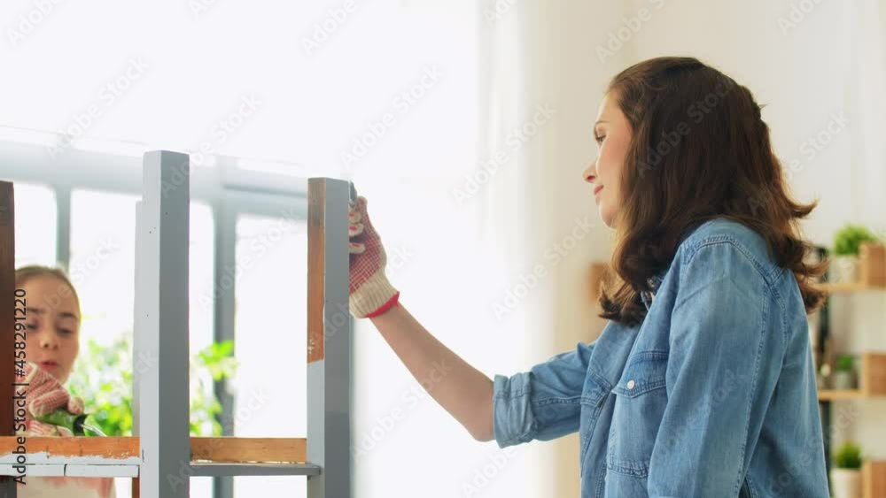 renovation, diy and home improvement concept - mother and daughter in gloves with paint roller and brush painting old wooden table in grey color at home renovation, diy and home improvement concept - mother and daughter in gloves with paint roller and brush painting old wooden table in grey color at home