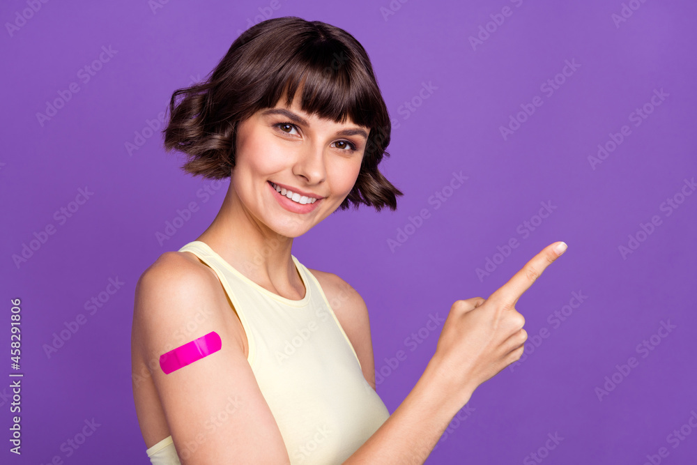 Photo of young brunette bob haired woman point finger empty space corona vaccine isolated on purple color background Photo of young brunette bob haired woman point finger empty space corona vaccine isolated on purple color background