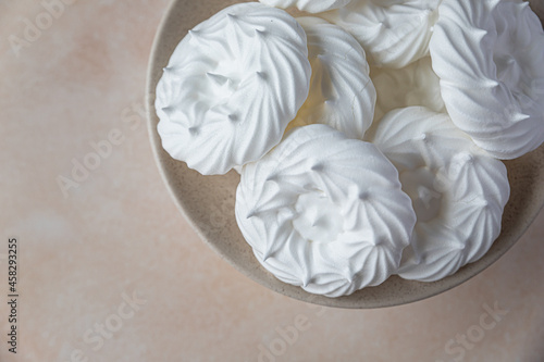 Plate with empty meringue nests, light stone background. Concept for a tasty sweet dessert.
