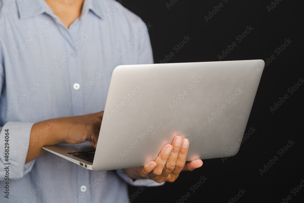 Businessman holding and using a laptop while standing with black background in the studio. Space for text. Business and technology concept Businessman holding and using a laptop while standing with black background in the studio. Space for text. Business and technology concept