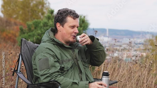 The tourist poured hot coffee from a thermos into a thermos lid. Travel accessories. Morning drink outdoors. Travel videos.