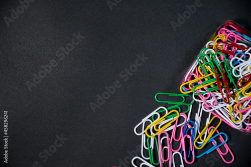 Group of colorful paper clips together with their boxes on a black background. Black space for your text