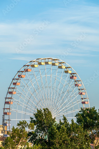 Ferris wheel in the amusement park as tourist attraction on the background of blue sky with copy space