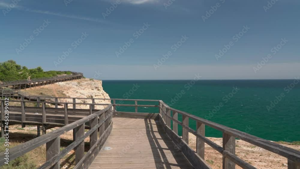 Wonderful view of the Portuguese coast of Carvoeiro in summer, walking along the wooden paths. Overlooking the blue sea. Shooting in motion with a stabilizer. Wonderful view of the Portuguese coast of Carvoeiro in summer, walking along the wooden paths. Overlooking the blue sea. Shooting in motion with a stabilizer.