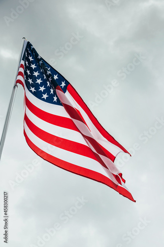 USA America flag waving in the wind over cloudy sky.