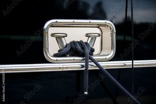 Tableau sur toile Stainless steel polished bollard with mooring rope on the dark blue hull of the super luxury yacht