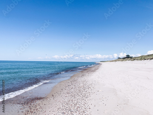 Wild white sand beach, empty beach, sea coastline, blue sky, azure water surface  © Oksana