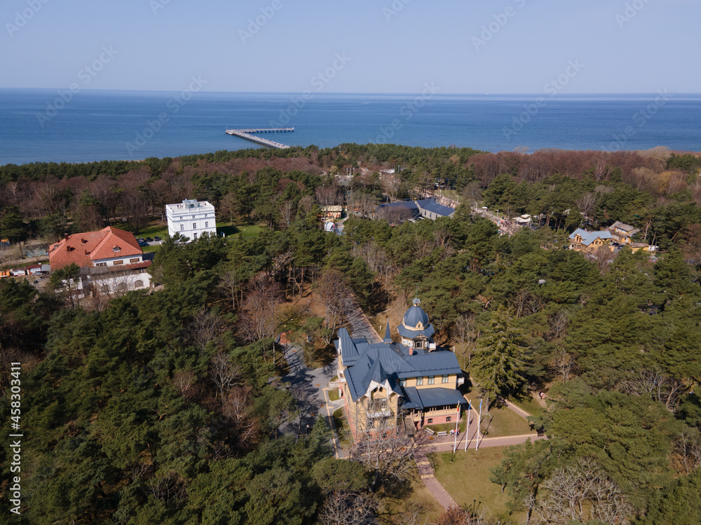 Obraz premium Aerial panoramic view of Palanga resort, Palanga city museum and other building among pines with a sea bridge in the distance in Baltic sea