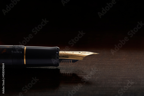Pena dourada de caneta tinteiro em macro sobre fundo de madeira escura photo