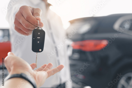Hand of business man gives the car key, Close-up image a man buys a car and receives keys from the seller. © chartphoto