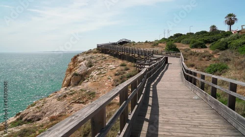 Wonderful view of the Portuguese coast of Carvoeiro in summer, walking along the wooden paths. Overlooking the blue sea. Shooting in motion with a stabilizer.