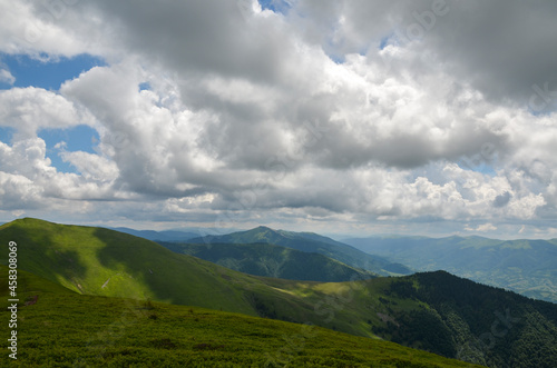 Beautiful scene, with mountain peaks covered green lush grass under cloudy sky. Classic Carpathian mountains landscape in summer