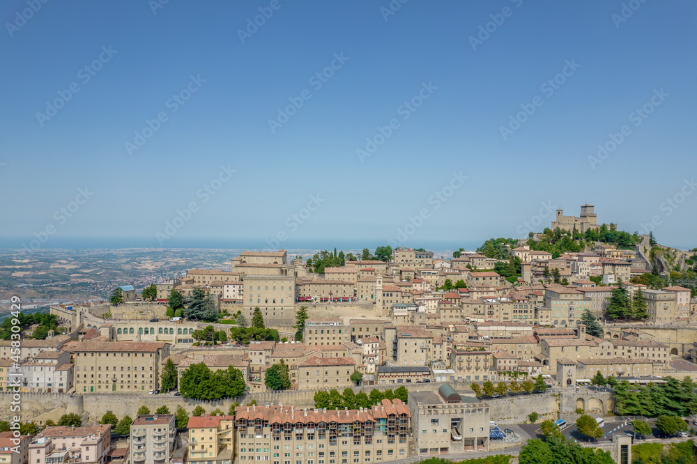 Aerial view of San Marino old town with old buildings and red roofs on the hill on a sunny day with clear sky