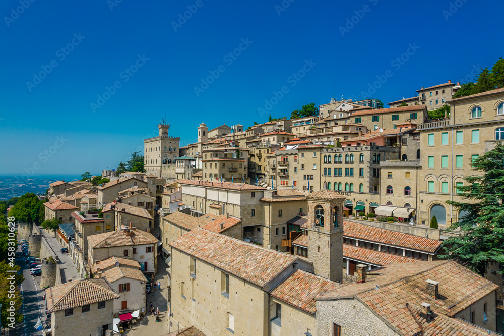 Aerial view of San Marino old town with old buildings and red roofs on the hill on a sunny day with clear sky