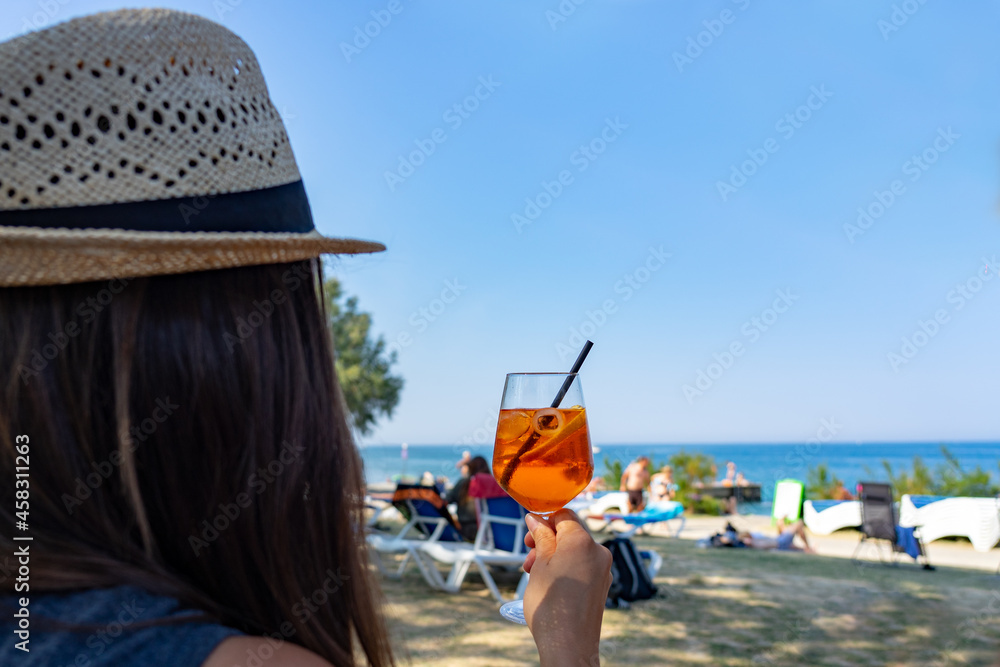 Fototapeta premium Woman drinking a long drink cocktail on the beach in Piran Slovenia