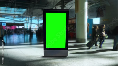 Green Screen Panel Airport People Walking Behind Billboard. Digital panel green screen inside an airport with people walking behind. Pre Keyed photo