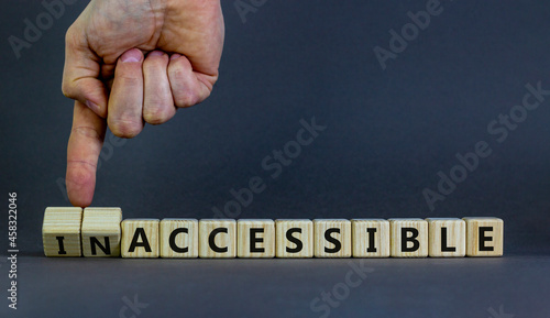 Accessible or inaccessible symbol. Businessman turns wooden cubes, changes the word Inaccessible to Accessible. Beautiful grey background, copy space. Business, accessible or inaccessible concept.