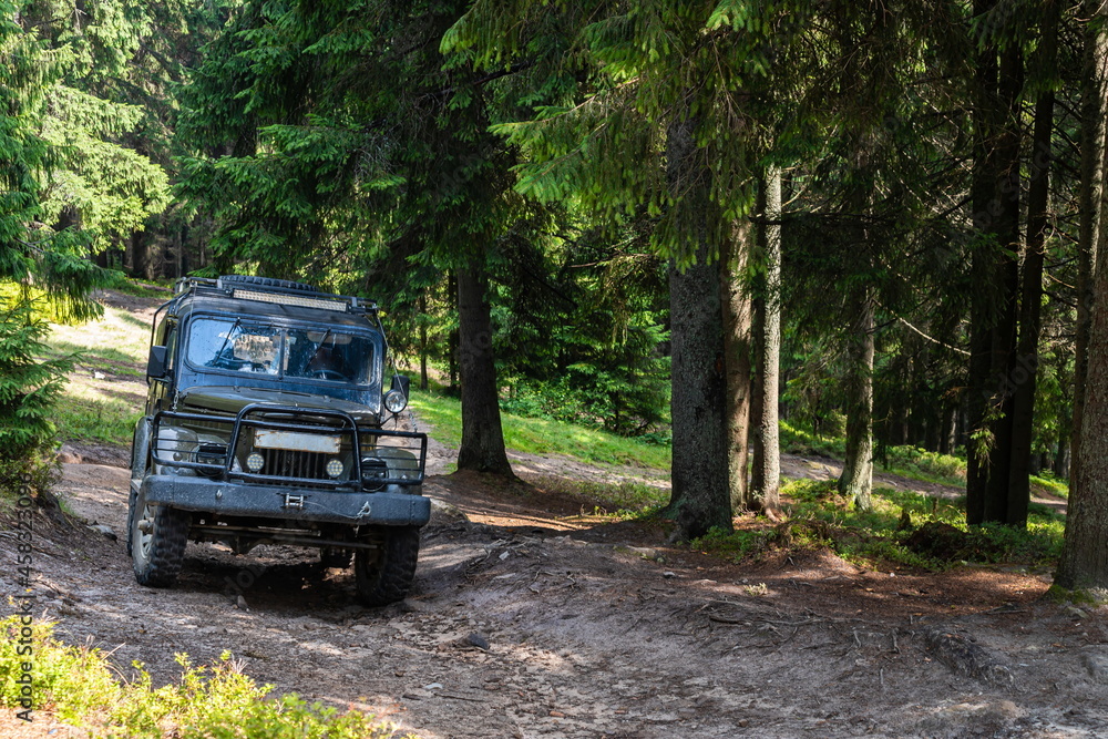 Old retro vintage 4x4 SUV on a dirt gravel dirt road in summer. Off-road car mountain safari adventure nature trip travel concept