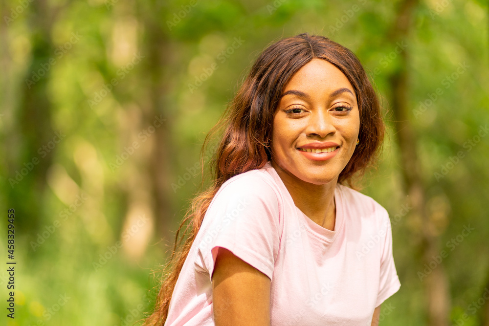 young black woman sitting on a bench in a park on a summer afternoon. young black woman sitting on a bench in a park on a summer afternoon.