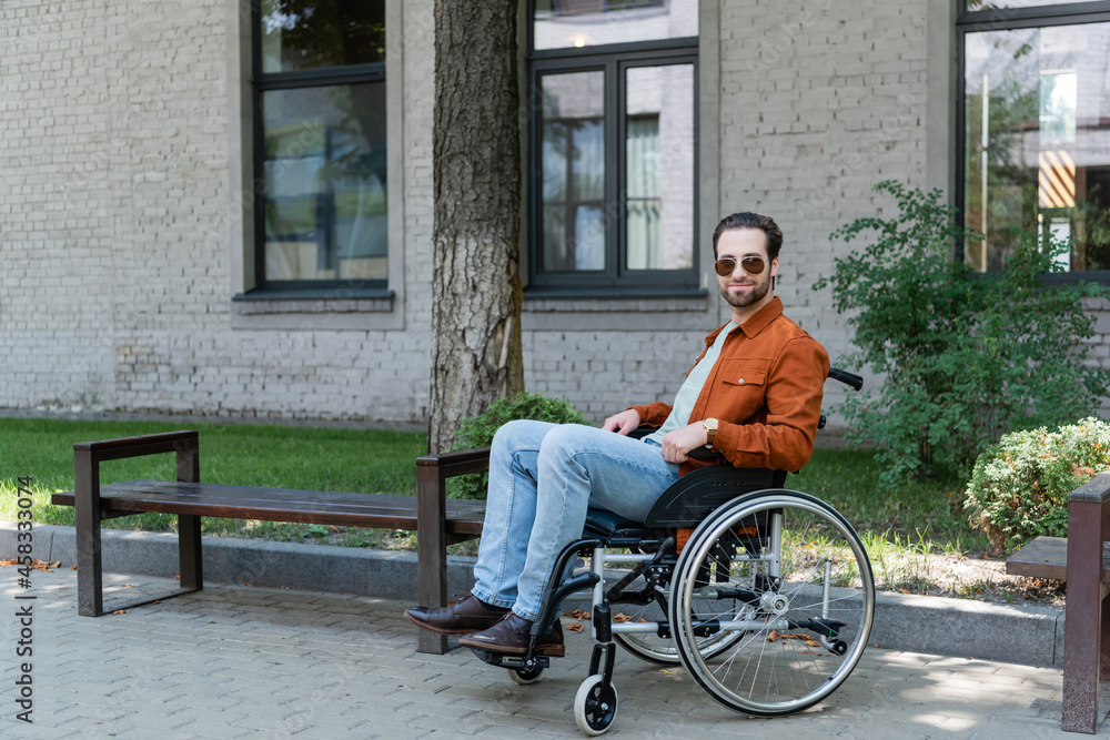young disabled man in wheelchair smiling at camera on urban street young disabled man in wheelchair smiling at camera on urban street