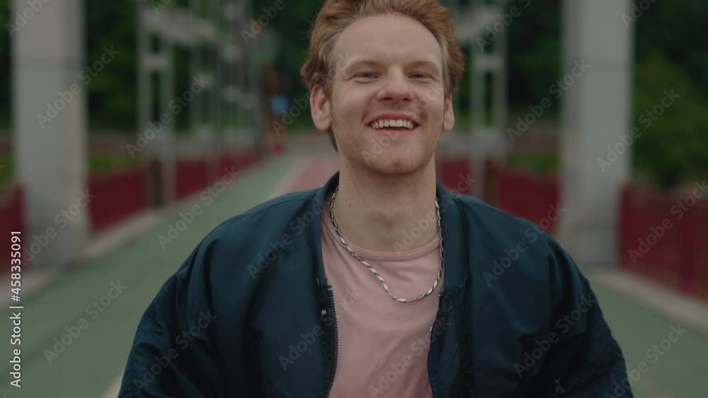 Carefree young man with red hair running on city bridge Carefree young man with red hair running on city bridge