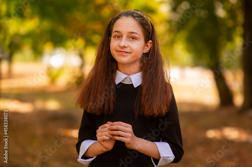 School concept. Little girl 11 or 12 years old in a dress on the background of nature in autumn.