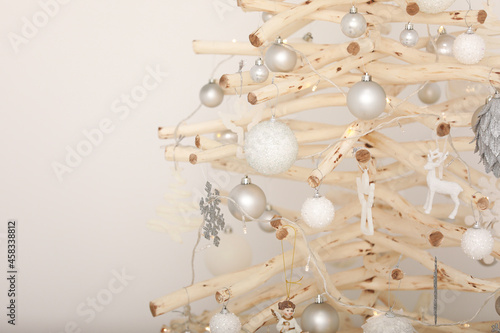 Christmas decoration. New Year's silver, white toys and with lights on a wooden Christmas tree. Christmas background for postcard. Scandinavian style