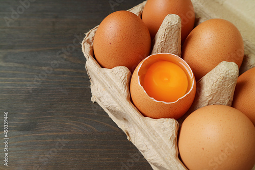 Fresh organic eggs with one of opened shell in a carton box