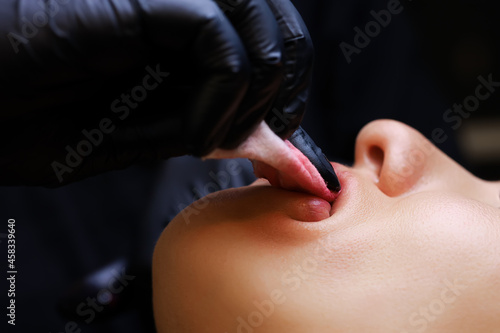 close-up the master erases the red pigments from the lips of the tattoo model with a sponge