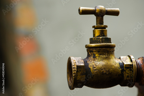 old brass water tap isolated on a light background. tap valve. old copper retro faucet on a rusty pipe. plumbing, repair, dismantling. Vintage close-up. outdoor water tap