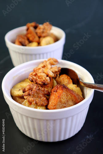Closeup Mouthwatering Banana Walnut Bread Pudding in a White Bowl on Black Table 