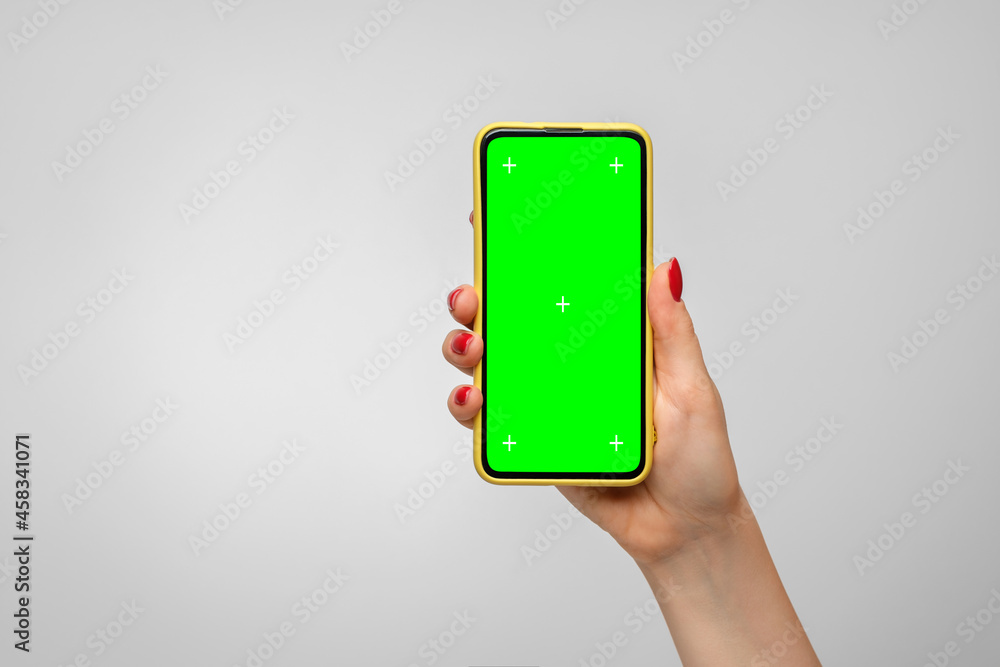Smartphone in a yellow case with a green screen in a woman's hand Smartphone in a yellow case with a green screen in a woman's hand