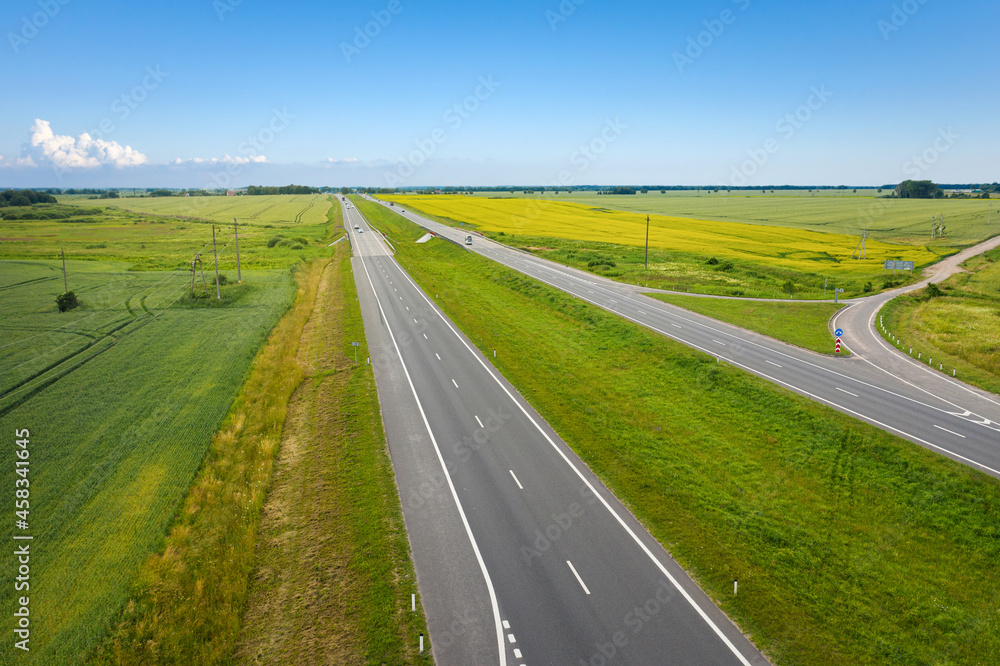 Asphalt highway through green summer field. Aerial view