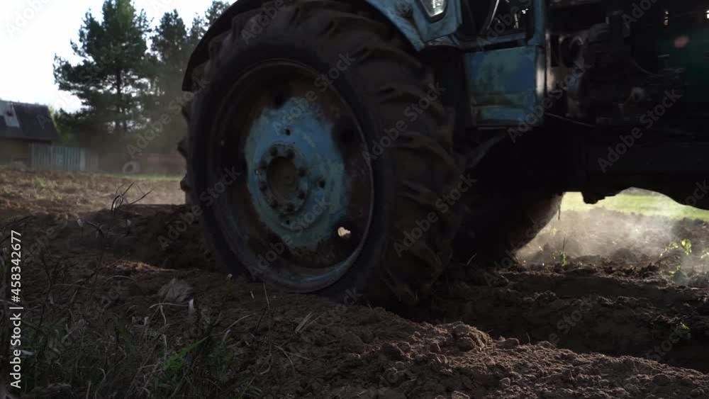 a tractor plows in a field against the background of a beautiful green forest. Agricultural work in the field, agribusiness, Sowing and harvesting of agricultural crops a tractor plows in a field against the background of a beautiful green forest. Agricultural work in the field, agribusiness, Sowing and harvesting of agricultural crops