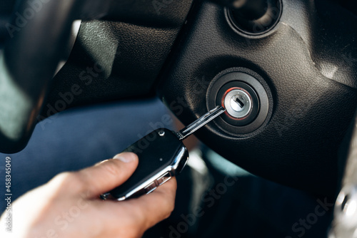 Selective focus of the male hand winds up the car ignition key, car driving and dashboard. Travel and transportation concept