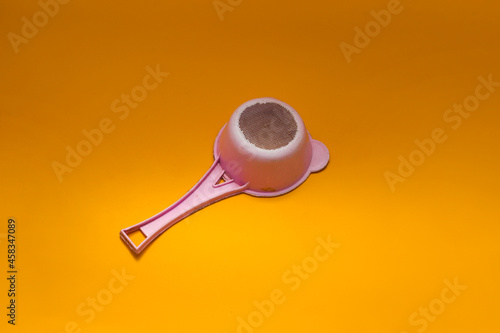 Old used pink plastic tea strainer (colander) isolated on orange background