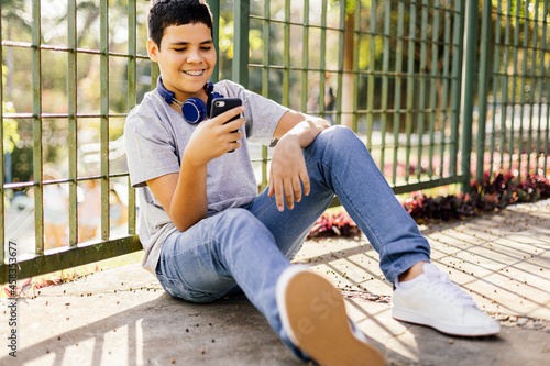 12 years old boy using smartphone outdoors.