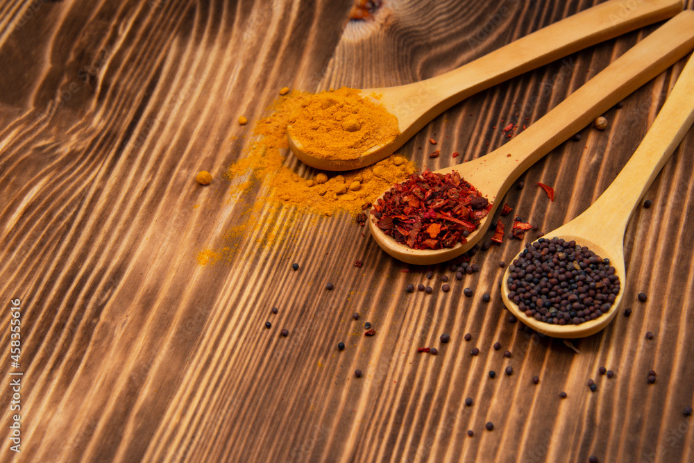 Dry different spices in spoons on wooden background Dry different spices in spoons on wooden background