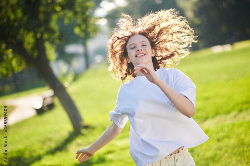 A ginger long-haired girl running in a park and looking happy A ginger long-haired girl running in a park and looking happy
