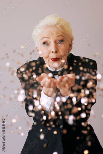 short hair stylish senior woman in tuxedo with glitter celebrating new year. Fun, lifestyle, style, age concept