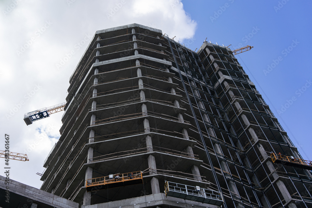 Construction of a high-rise building on the background of a blue cloudy sky in the city