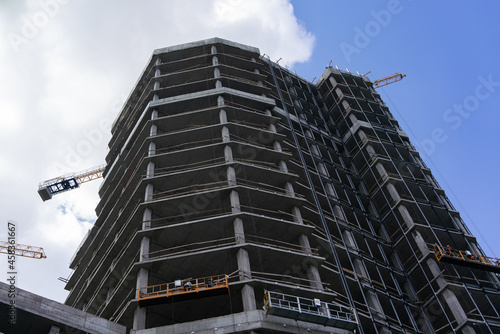 Construction of a high-rise building on the background of a blue cloudy sky in the city