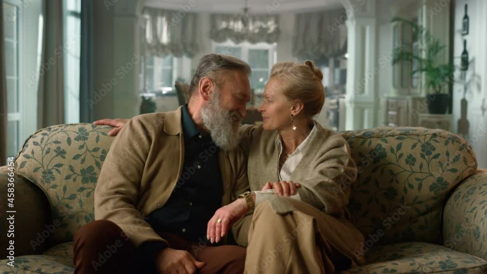Smiling elderly couple talking on couch in living room. Happy senior people Smiling elderly couple talking on couch in living room. Happy senior people