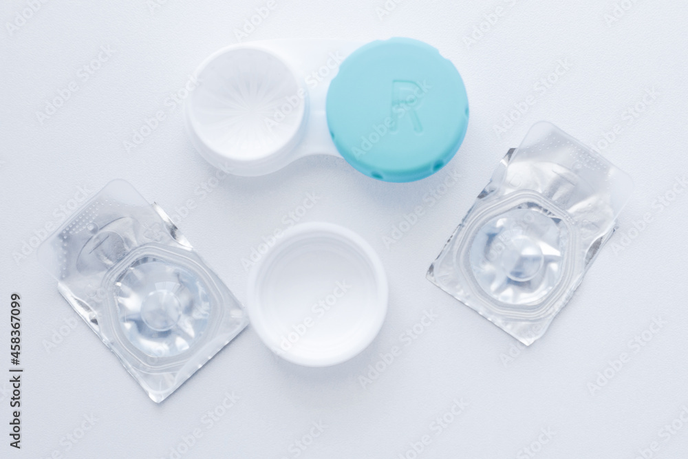 The lens container and two sealed lenses lie in the center on a white background. top view, flat lay, copy space, isolate The lens container and two sealed lenses lie in the center on a white background. top view, flat lay, copy space, isolate